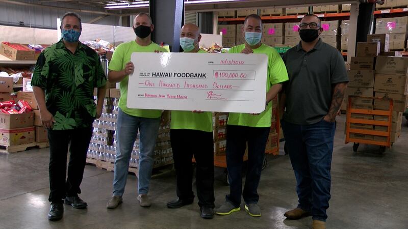 Ron Mizutani, the president of the Hawaii Foodbank, is presented with a $100,000 donation by...