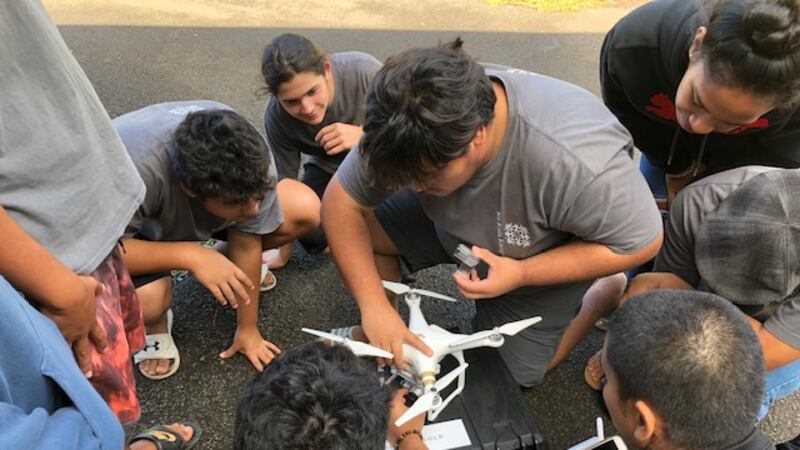 High school students from Ke Kula Kaiapuni O Anuenue School prepare a drone for flight....