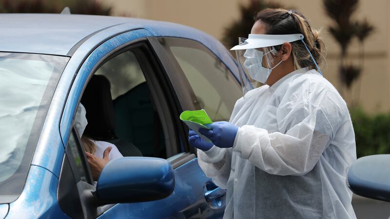 A medical worker talks to a person in their car outside an Urgent Care Hawaii medical clinic...