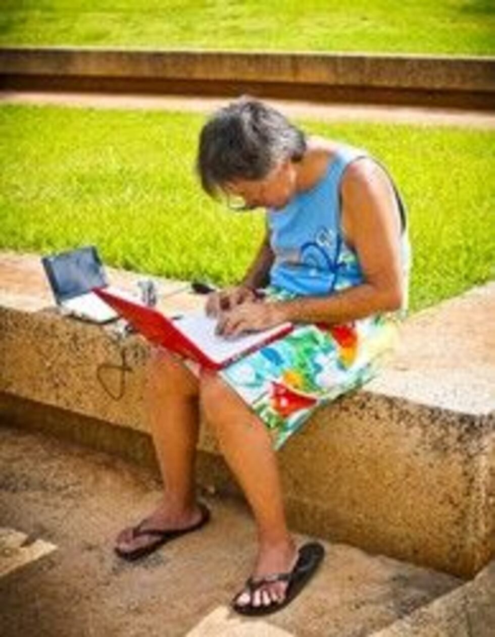 Ryan Suenaga in board shorts and with his lap top computer.