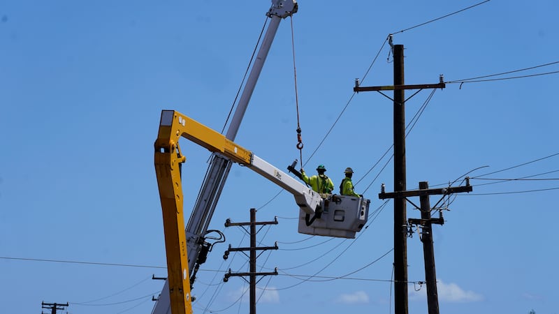 Linemen work on poles, Sunday, Aug. 13, 2023, in Lahaina, Hawaii, following a deadly wildfire...